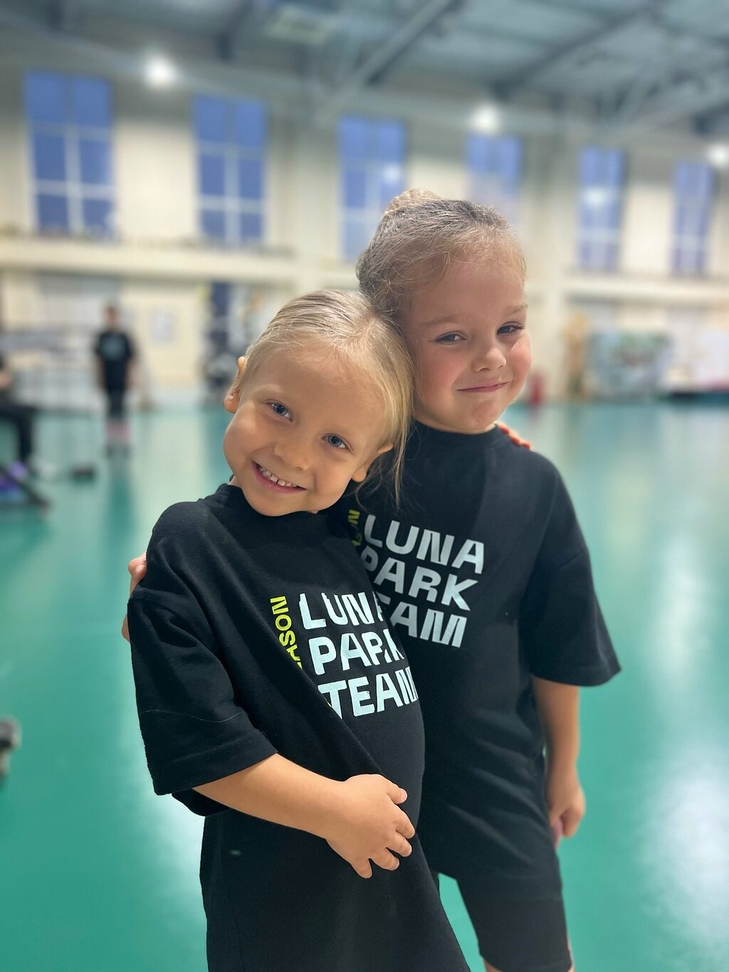 Две малышки в футболках Luna Park Team в зале школы